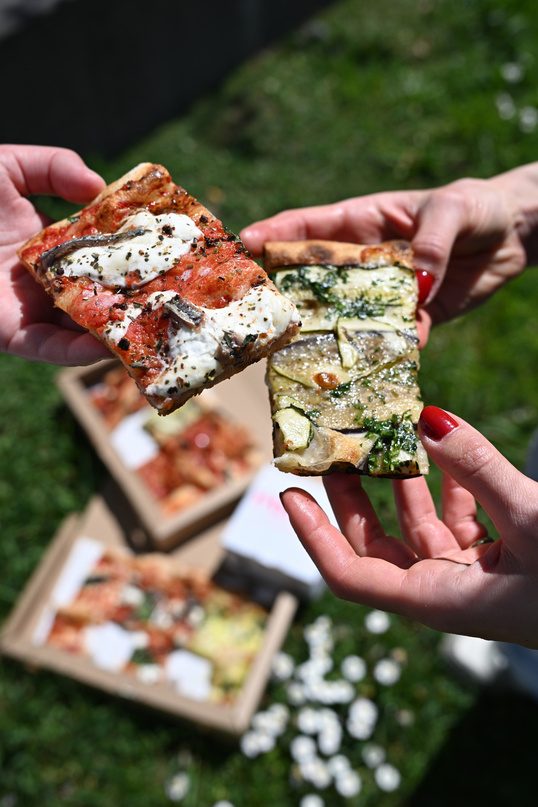 Slices of pizza al taglio shared outdoors